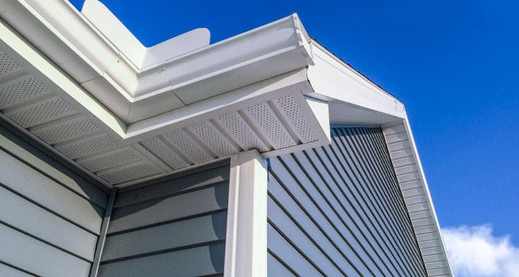 Blue sky with house and new siding and gutters.